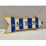 APAINTED SIGN IN THE SHAPE OF AN ARROW WITH THE WORDS 'MAD HOUSE' 82CM X 32CM