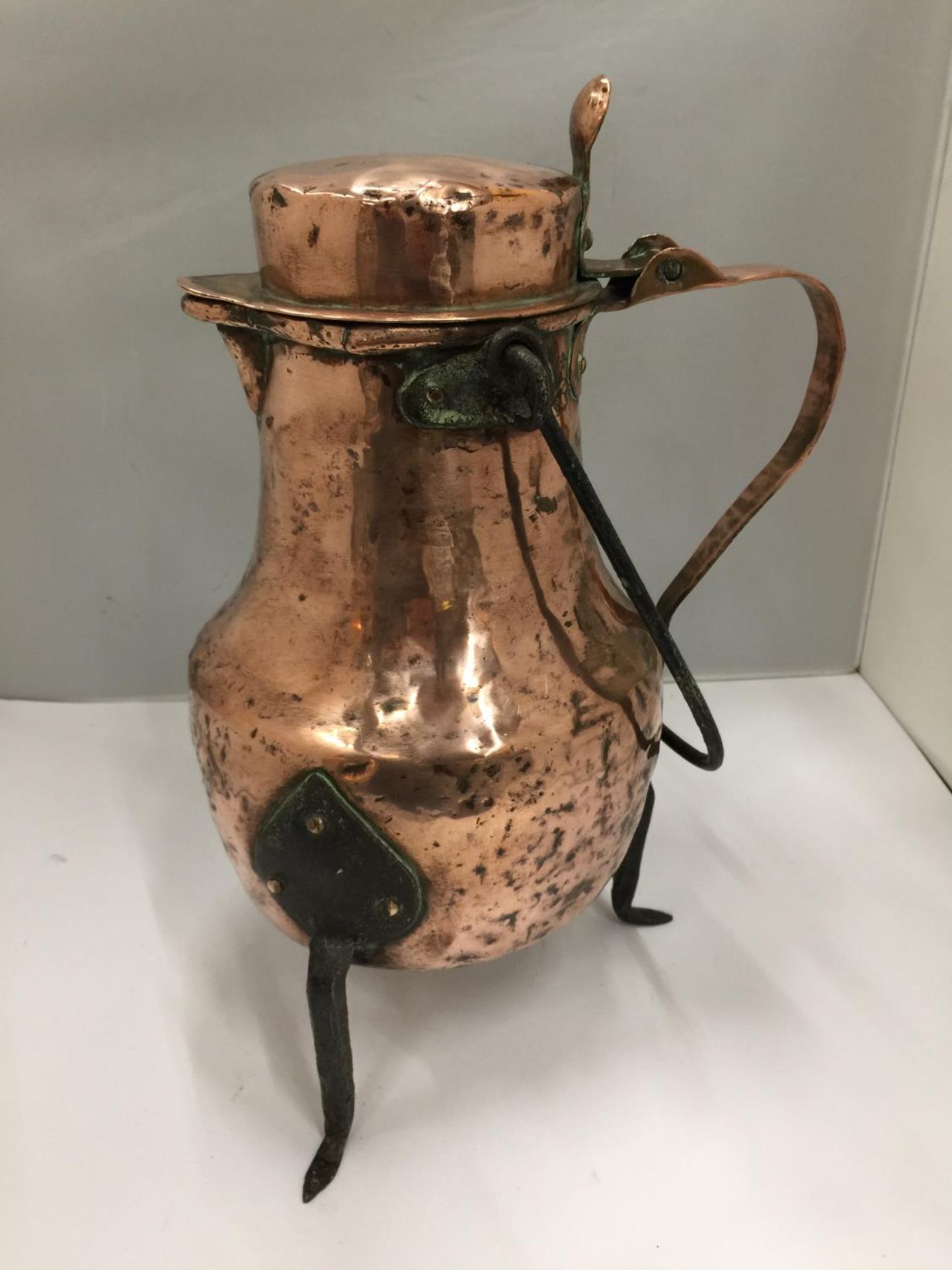 A VINTAGE COPPER POT WITH THREE IRON LEGS AND A HANDLE 34CM HIGH