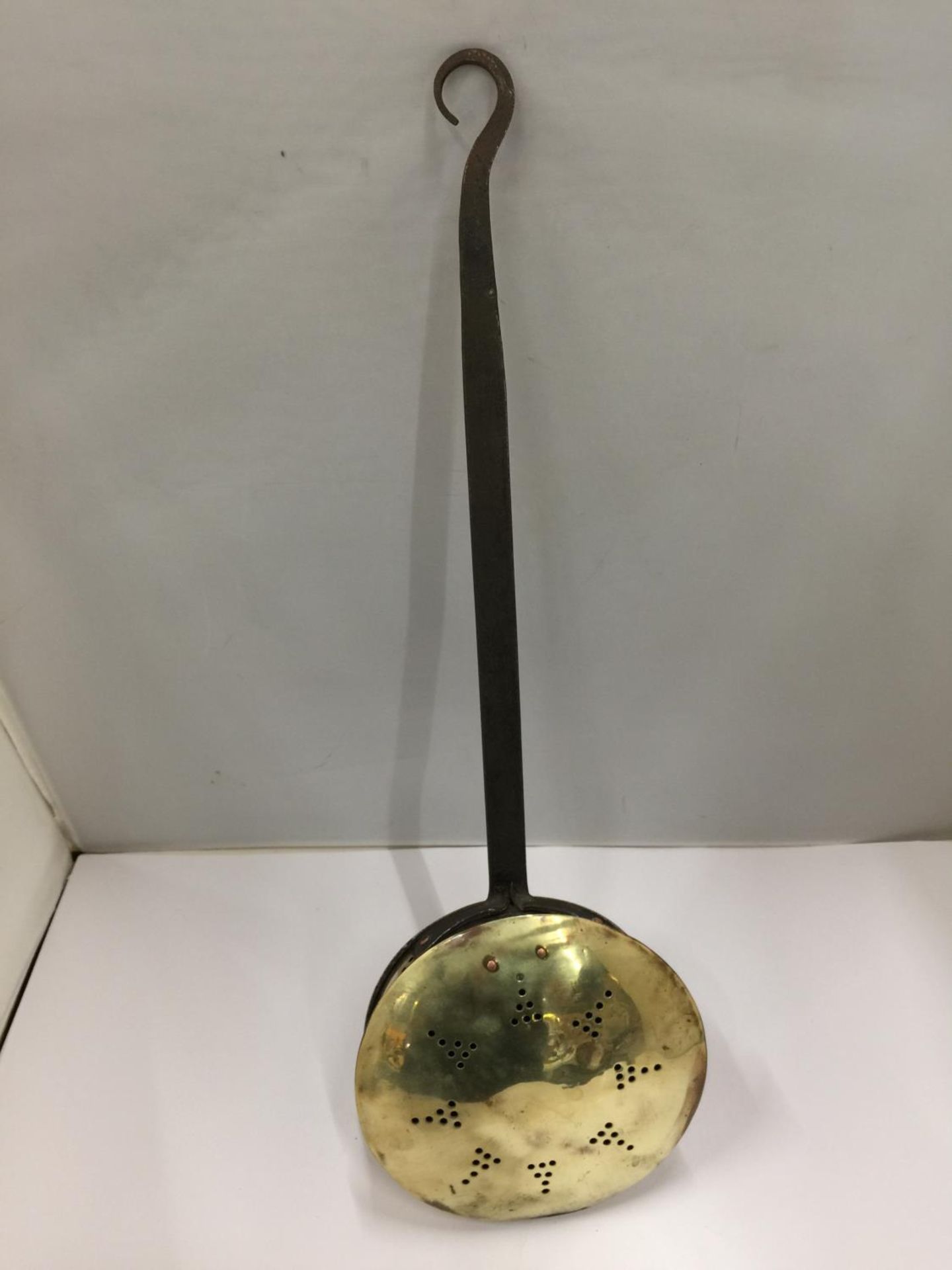 A BRASS CHESTNUT ROASTING PAN WITH CAST HANDLE