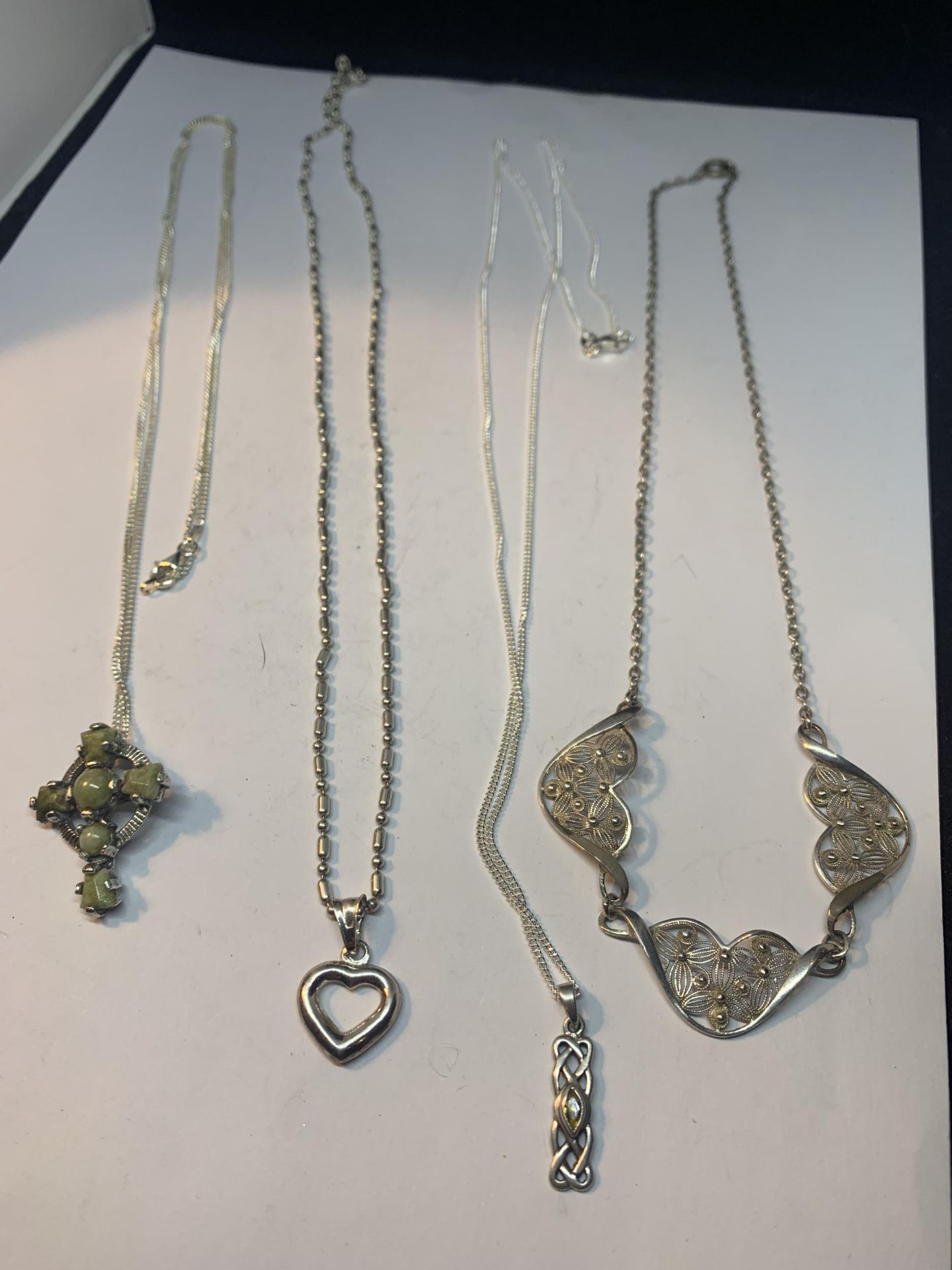 FOUR MARKED SILVER NECKLACES THREE WITH PENDANTS AND ONE WITH AN IN LINE FLOWER DESIGN