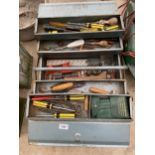 A METAL TOOL BOX CONTAINING AN ASSORTMENT OF TOOLS TO INCLUDE STILSONS, SCREW DRIVERS AND A RASP ETC