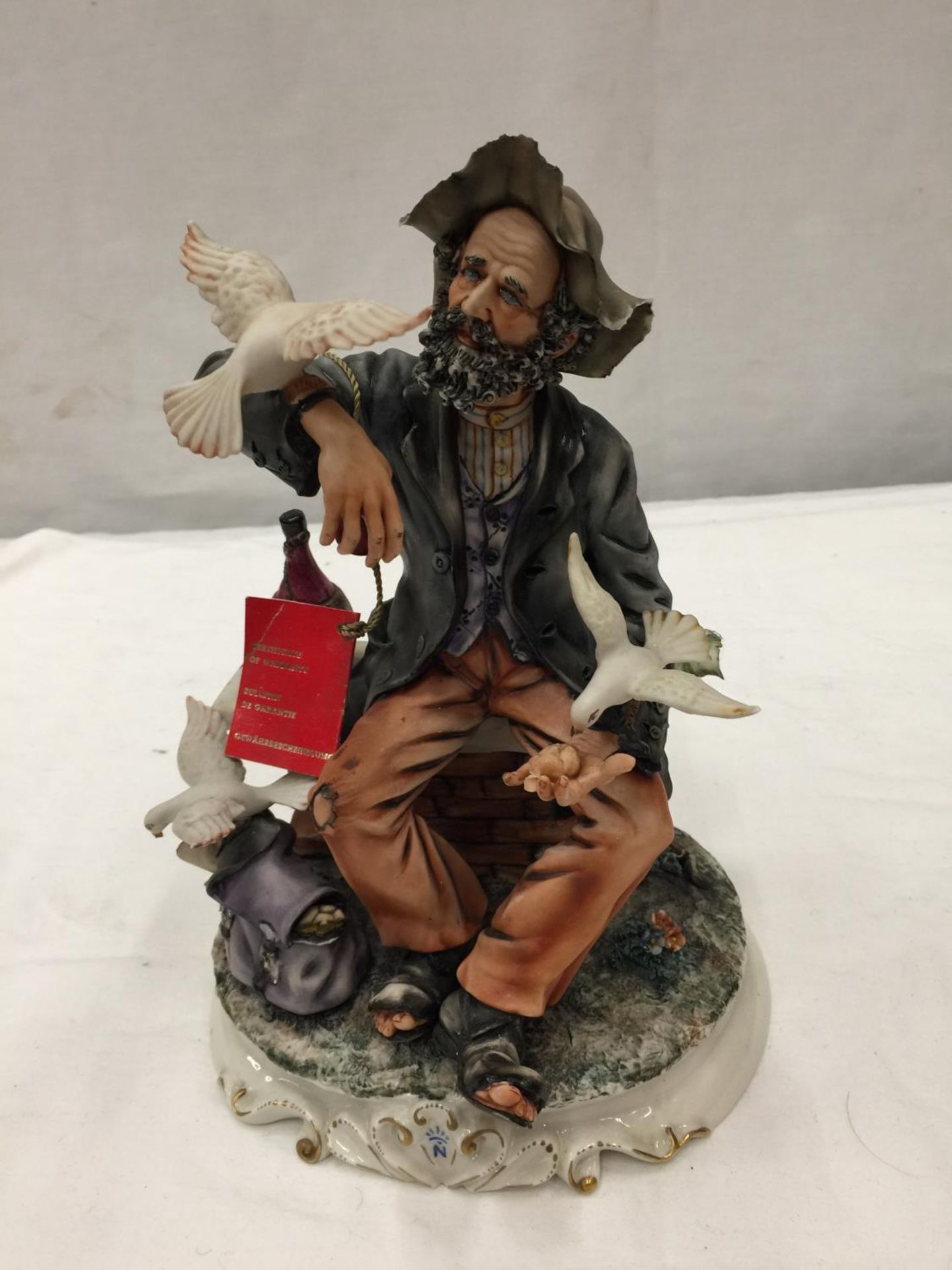 A CAPODIMONTE PORCELAIN FIGURE OF A SEATED MAN FEEDING DOVES A/F