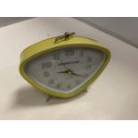 A RETRO LOOKING YELLOW ALARM CLOCK