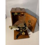 A VINTAGE BRASS AND CAST MICROSCOPE WITH THREE LENSES IN A MAHOGANY BOX WITH BRASS FITTINGS. AN