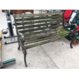 A WOODEN SLATTED GARDEN BENCH WITH HEAVY CAST BENCH ENDS