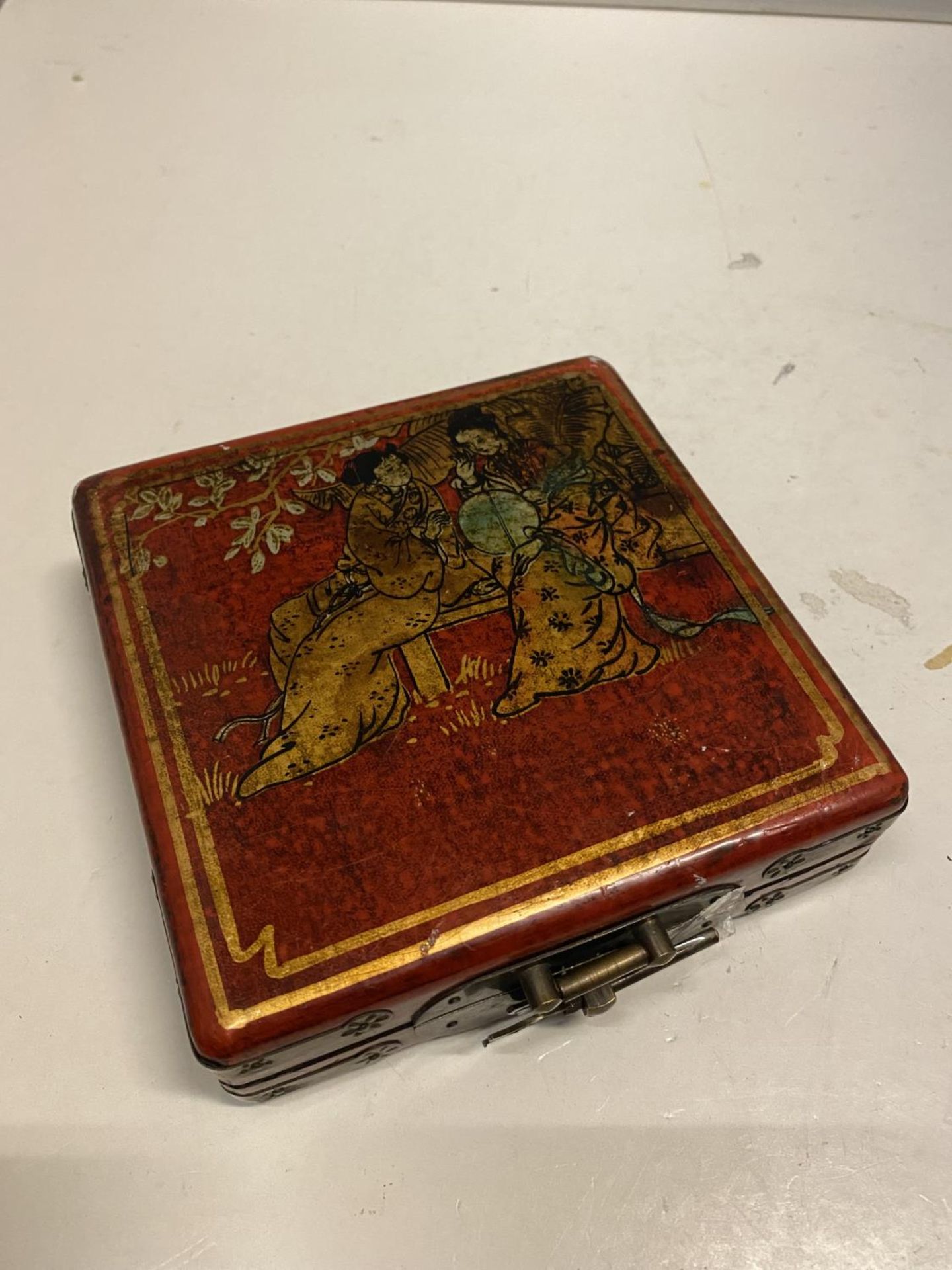 AN ORIENTAL DECORATED TRINKET BOX WITH A PICTURE OF GEISHA GIRLS AGAINST A RED BACKGROUND SIZE