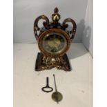 AN ORNATE TREACLE GLAZED MANTLE CLOCK WITH KEY (REPAIR TO DECORATION)