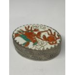 AN ORNATE WHITE METAL BOX WITH INTERNAL MIRROR AND AN ENAMEL LID WITH ORIENTAL DRAGON DESIGN