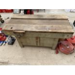 A LARGE VINTAGE WORK BENCH ENCLOSING TWO LOWER CUPBOARD DOORS AND A RECORD BENCH VICE