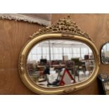 A DECORATIVE OVAL GILT FRAMED WALL MIRROR