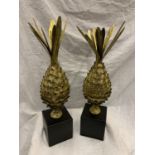 A PAIR OF GILDED PINEAPPLES ON A BLACK WOODEN BASE 60CM TALL