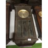 A 1930'S WALL CLOCK WITH PENDULUM, KEY AND A GLAZED BEVELLED DOOR