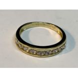 A 9 CARAT GOLD RING WITH NINE IN LINE CLEAR STONES SIZE K