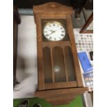 A 1930'S WALL CLOCK WITH PENDULUM AND A GLAZED BEVELLED DOOR