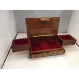 A POSSIBLY TEAK MUSICAL JEWELLERY BOX WITH MARQUETRY STYLE DECORATION AND RED FITTED INTERIOR SIZE