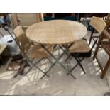 A WICKER/RATTAN BISTRO SET COMPRISING OF A ROUND TABLE AND TWO CHAIRS WITH DECORATIVE WROUGHT IRON