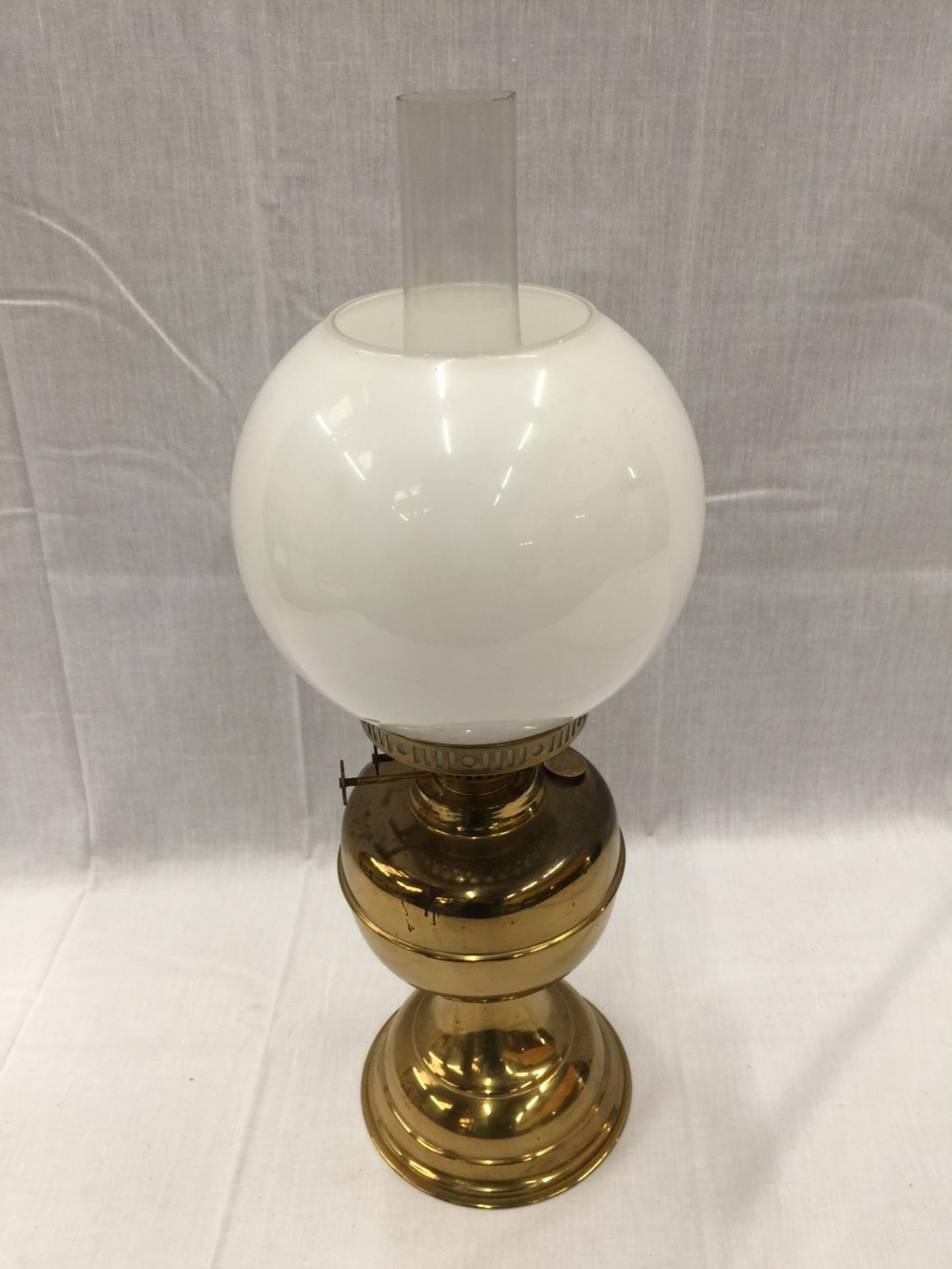 A HEAVY BRASS OIL LAMP WITH GLASS CHIMNEY AND MILK GLASS SHADE, HEIGHT APPROX 50CM