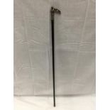 AN EBONISED WALKING STICK WITH A WHITE METAL HANDLE DEPICTING A NUDE LADY