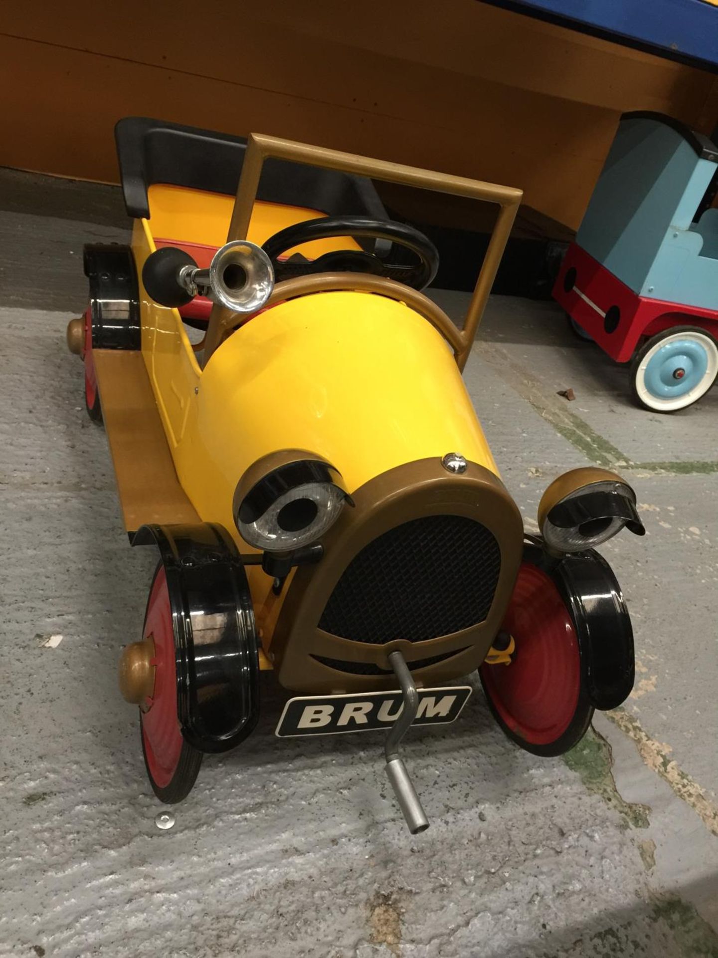 A BRUM PEDAL CAR WITH WORKING HORN AND CRANK HANDLE