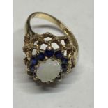 A MARKED 9 CARAT GOLD RING WITH A CENTRAL OPAL SURROUNDED BY TEN SAPPHIRES SIZE P WITH A