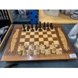 A WOODEN INLAID CHESS BOARD COMPLETE WITH THE PIECES. TOP OPENS FOR STORAGE