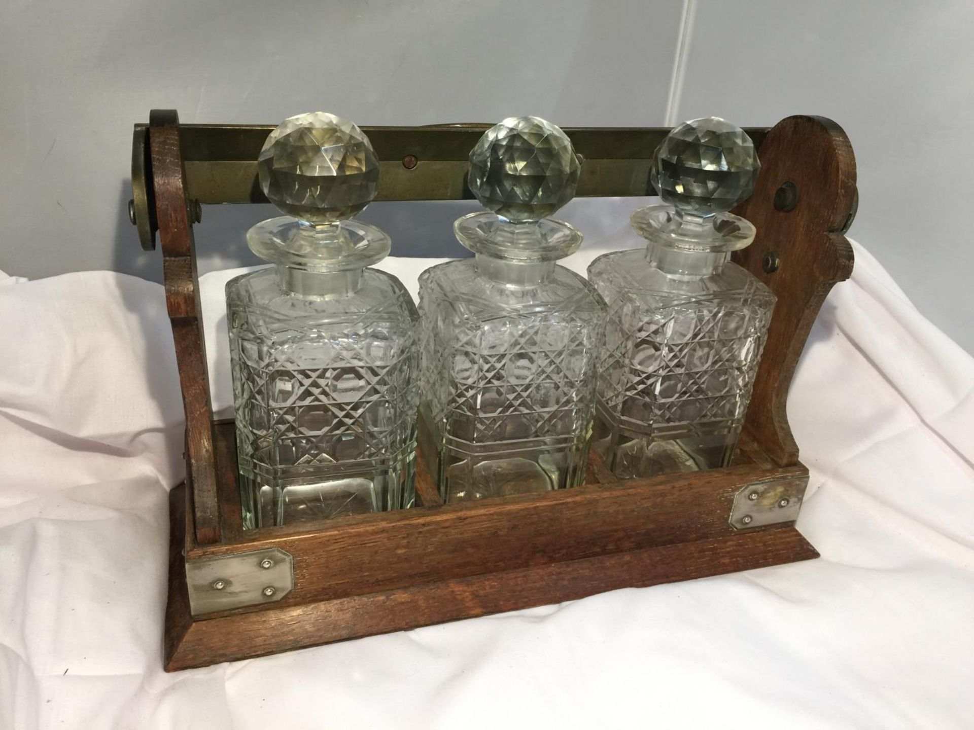 A BETJEMANN LONDON PATENT 62082 OAK FRAMED AND BRASS TANTALUS WITH THREE DECANTERS AND A KEY - Image 4 of 4