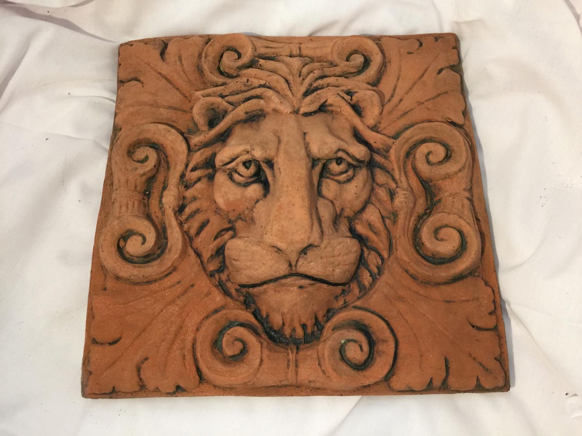 A TERRACTTA STONE WALL PLAQUE DEPICTING A LIONS HEAD 30CM X 30CM