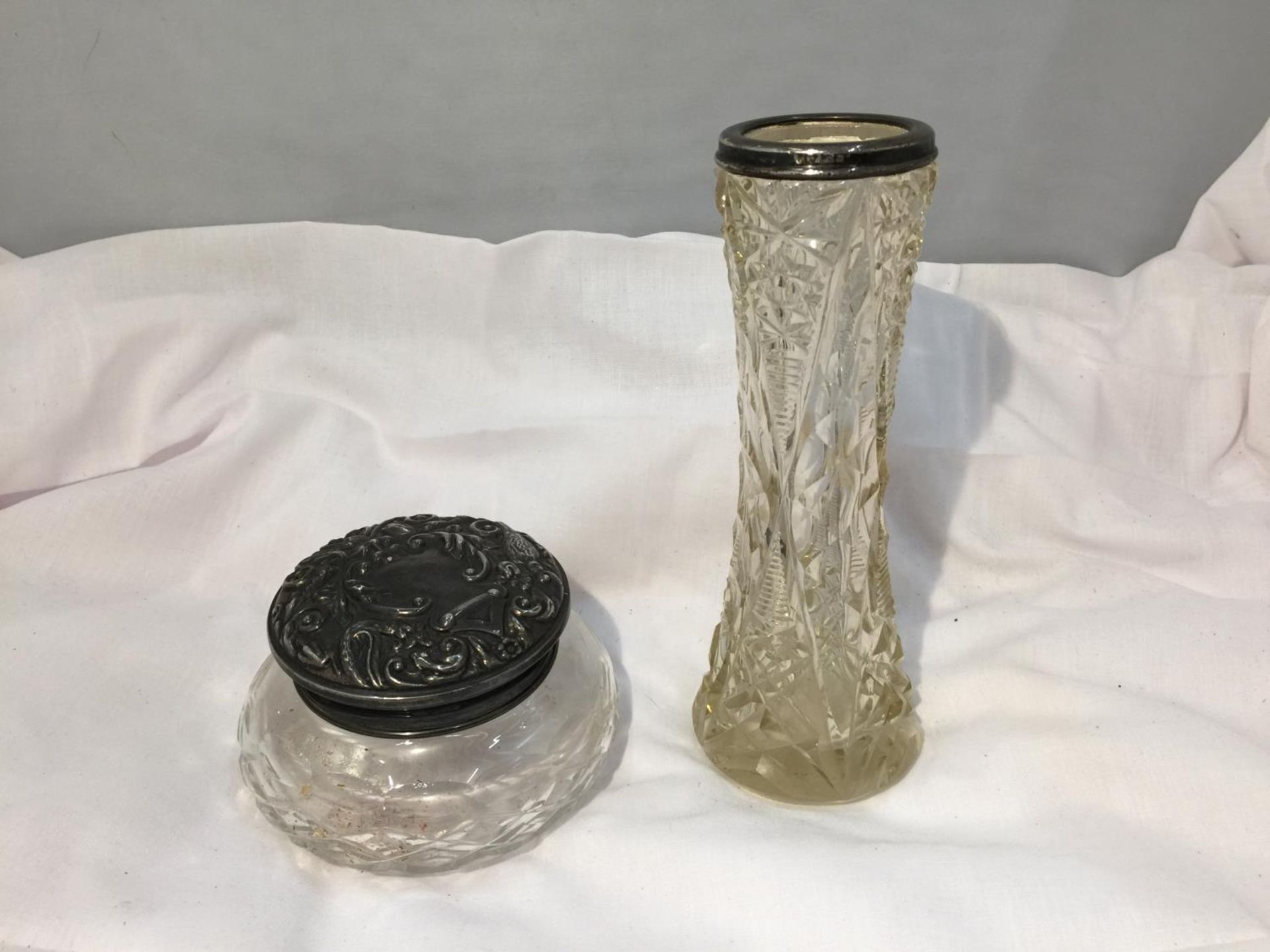 TWO CUT GLASS ITEMS ONE A JAR WITH AN ORNATE HALLMARKED BIRMINGHAM SILVER TOP AND A VASE WITH A