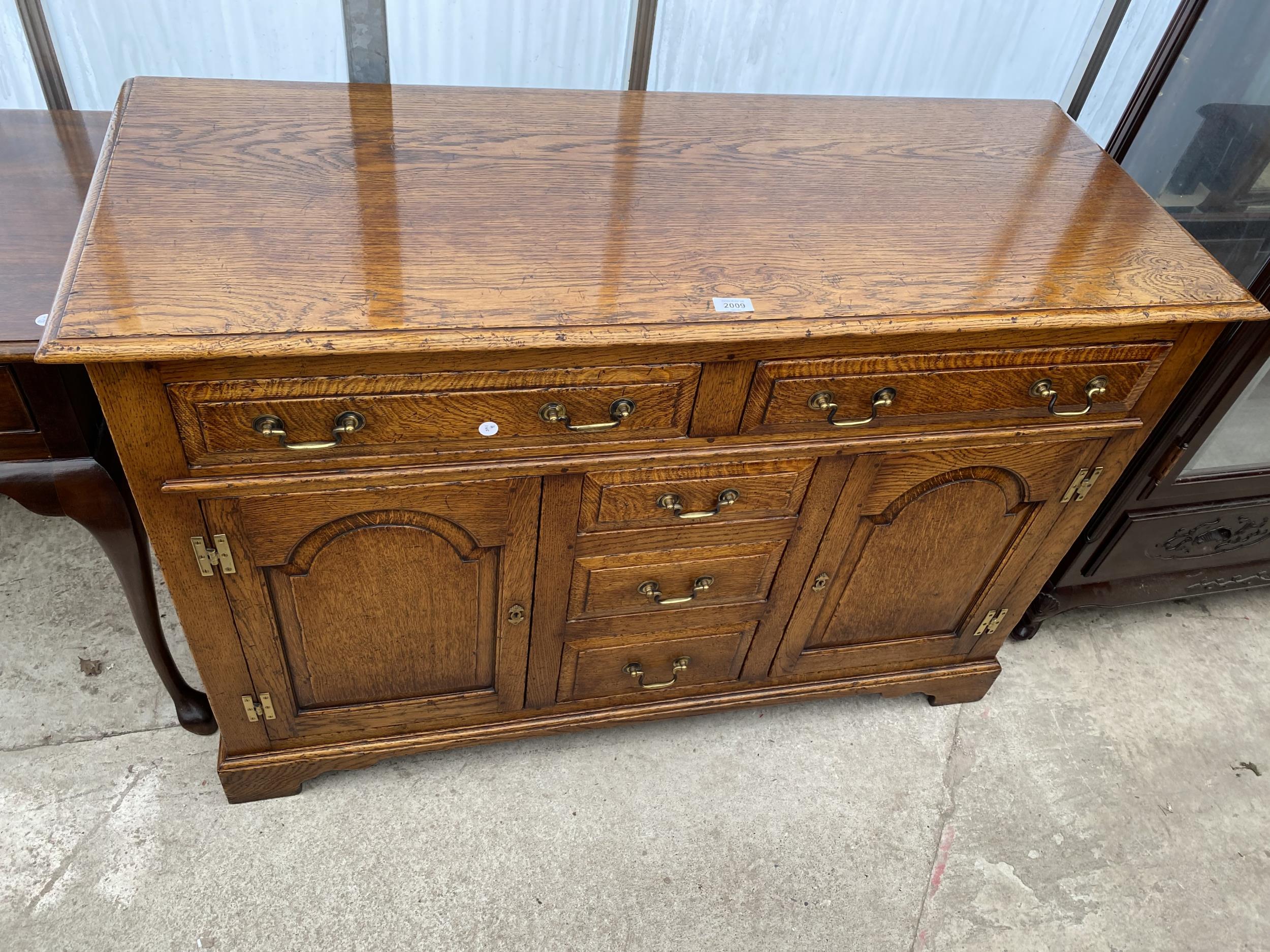 A GEORGE III STYLE LIGHT OAK DRESSER BASE ENCLOSING THREE SHORT AND TWO LONG DRAWERS AND TWO