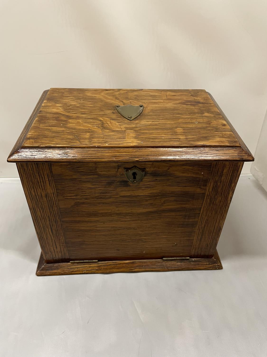 AN EARLY 20TH CENTURY OAK STATIONARY BOX WHICH OPENS TO A LEATHER WRITING DESK, SHIELD ON THE LID.