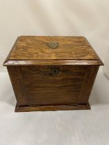 AN EARLY 20TH CENTURY OAK STATIONARY BOX WHICH OPENS TO A LEATHER WRITING DESK, SHIELD ON THE LID.
