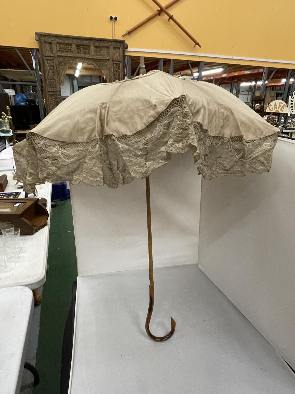 A VINTAGE CREAM LACE PARASOL WITH A WOODEN HANDLE