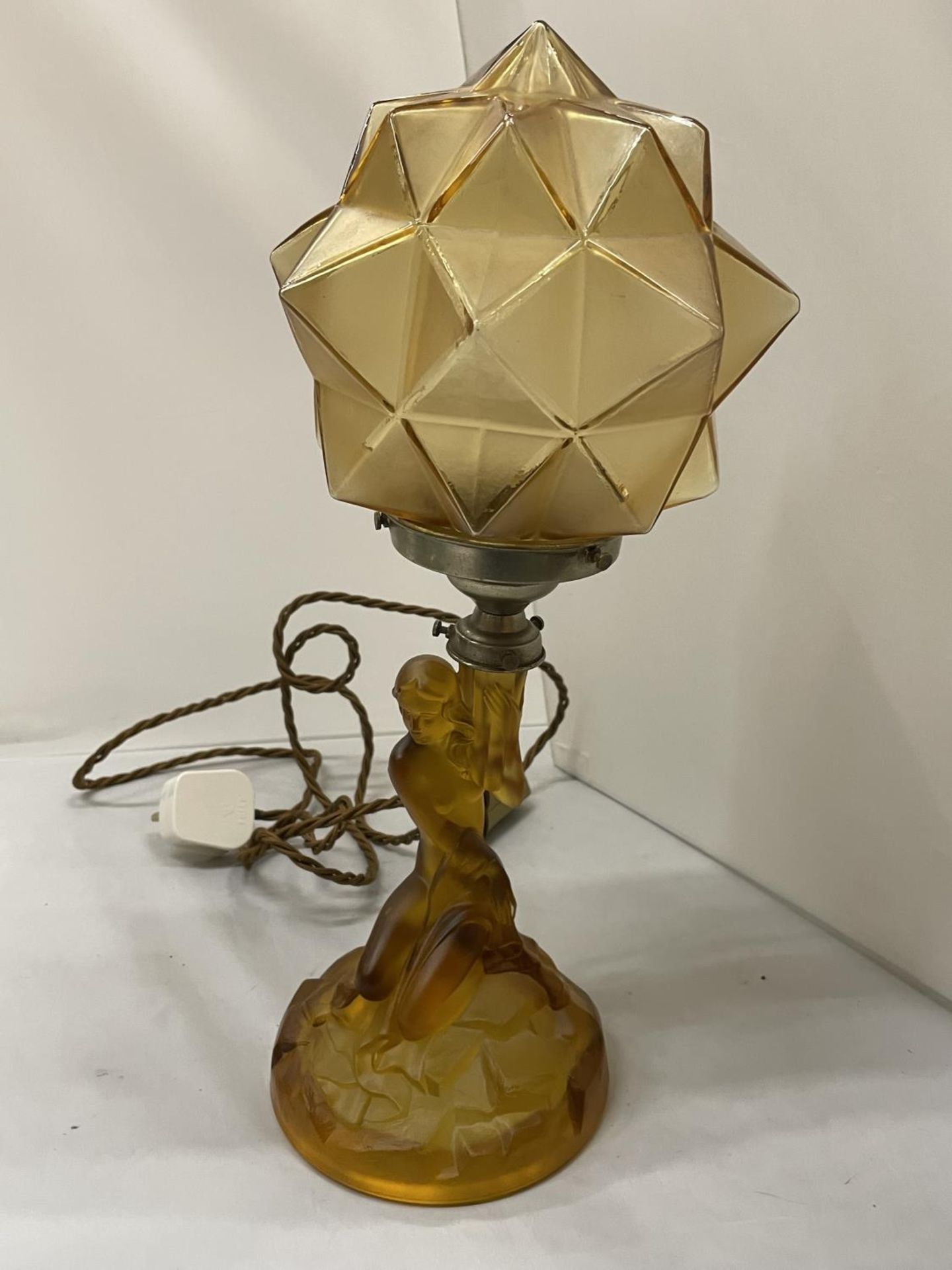 AN ART DECO STYLE AMBER COLOURED GLASS LAMP WITH THE BASE IN THE FORM OF A LADY AND A GEOMETRIC