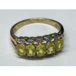 A 9 CARAT GOLD RING WITH A LINE OF FIVE CITRINE COLOURED STONES LINED EACH SIDE WITH DIAMOND CHIPS