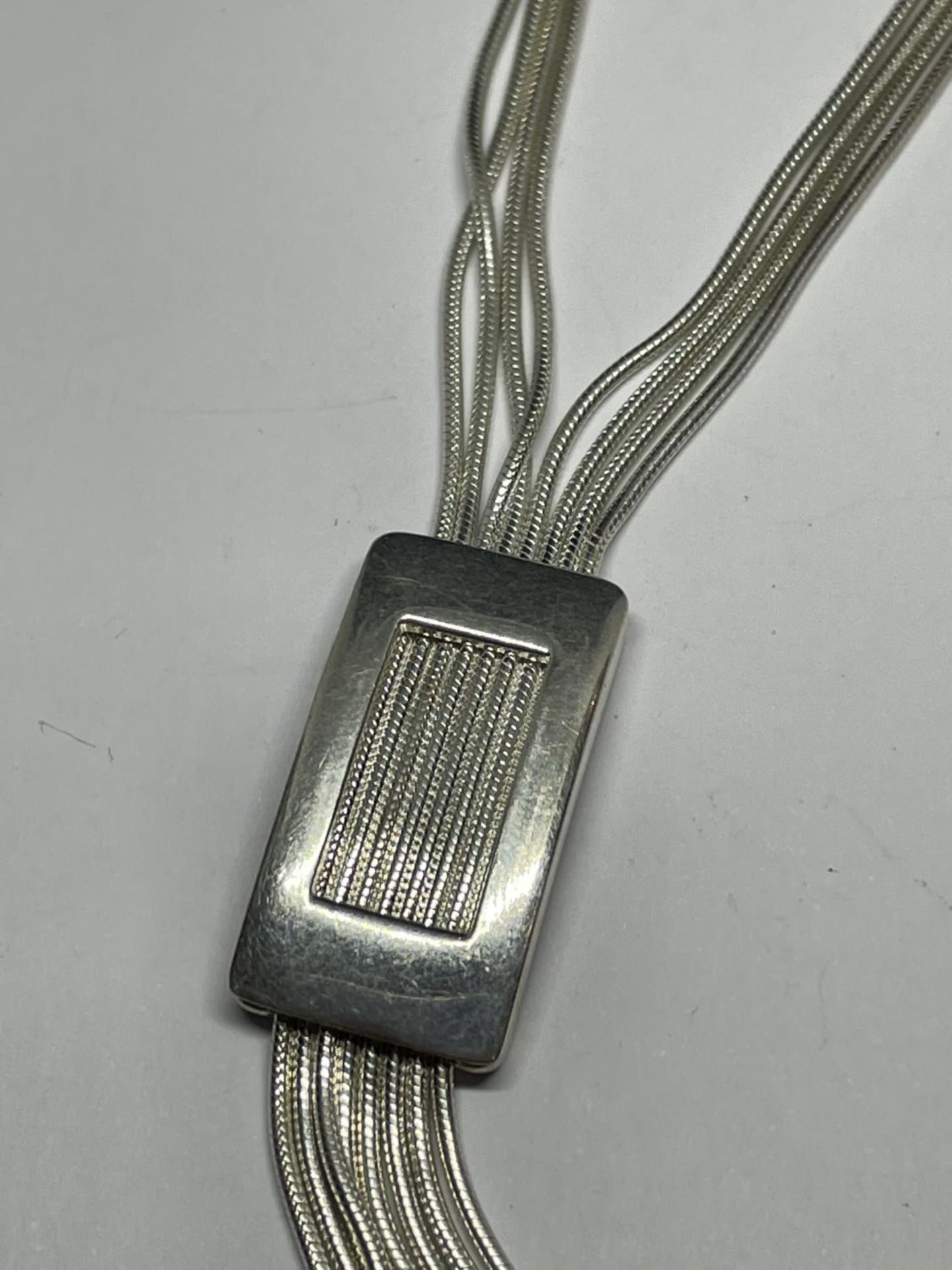 A MODERN STYLE FOUR STRAND MARKED SILVER NECKLACE WITH INTEGRATED OBLONG PENDANT AND TASSELS - Image 3 of 4