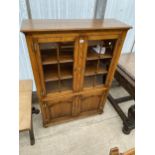A GEORGE III STYLE OAK TWO DOOR GLAZED BOOKCASE WITH ARCHED PANEL DOORS TO THE BASE, WITH H-BRASS