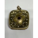 AN ORNATE 9 CARAT GOLD SQUARE SHAPED LOCKET WITH CENTRE RED STONE STAMPED S.B.CO TO THE INSIDE 2.5