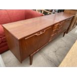 A RETRO TEAK SIDEBOARD ENCLOSING FOUR CUPBOARDS AND THREE DRAWERS, 82" WIDE