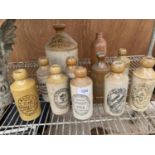 AN ASSORTMENT OF STONE WARE BOTTLES ALL BEARING VARIOUS NAMES TO INCLUDE 'J.W.GREENWOOD', 'EQUITABLE