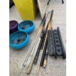 AN ASSORTMENT OF VARIOUS POOL CUES AND A CUE HOLDER