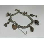 A MARKED SILVER CHARM BRACELET WITH SEVEN CHARMS TO INCLUDE A HORSES HEAD, HEDGEHOG, PALM TREE, SWAN