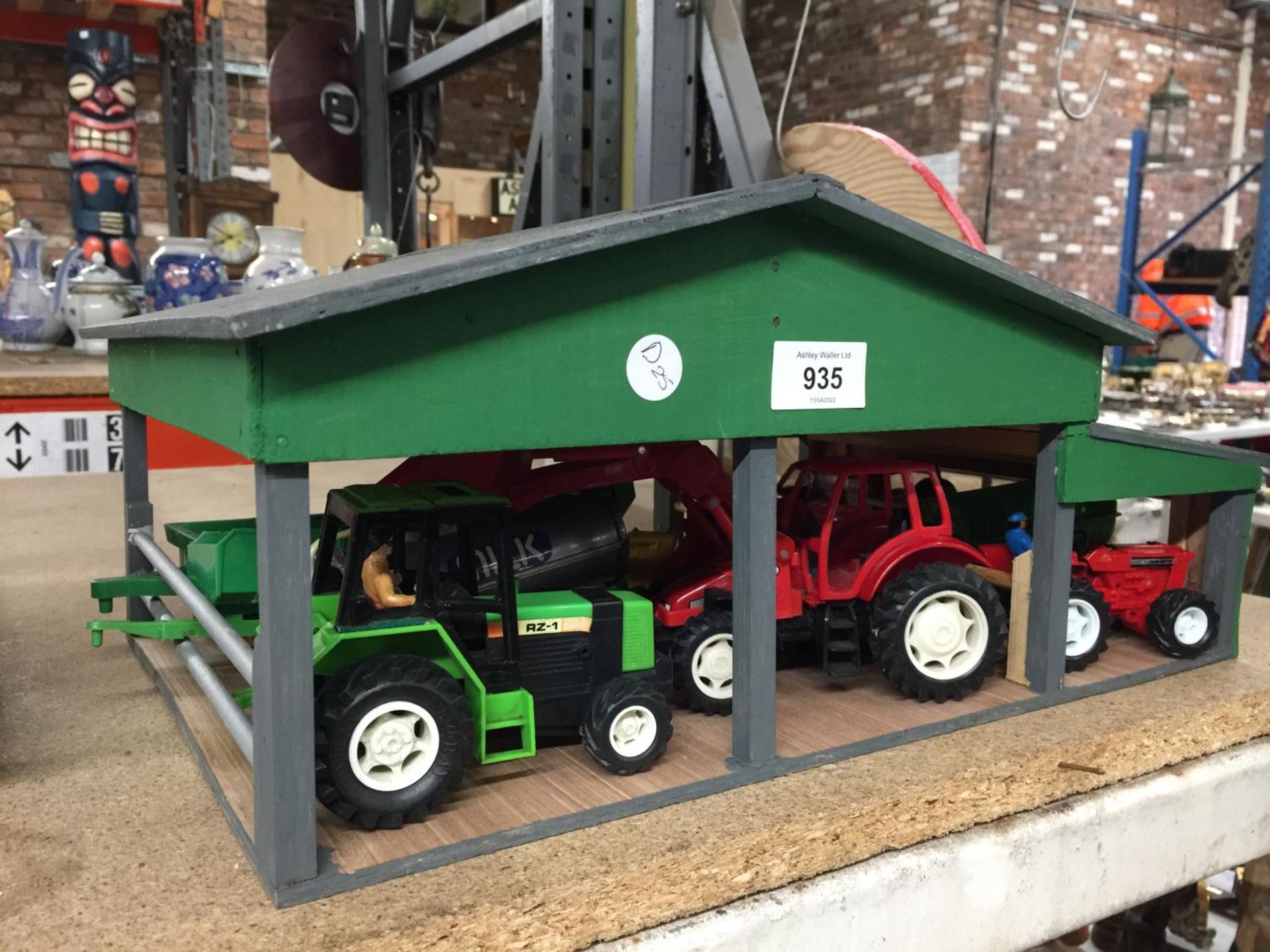 A HANDMADE WOODEN OPEN BARN CONTAINING TRACTORS, TRAILERS, ETC