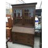 AN OAK ART NOUVEAU BUREAU BOOKCASE WITH GLAZED AND LEADED UPPER PORTION (A/F), 48" WIDE