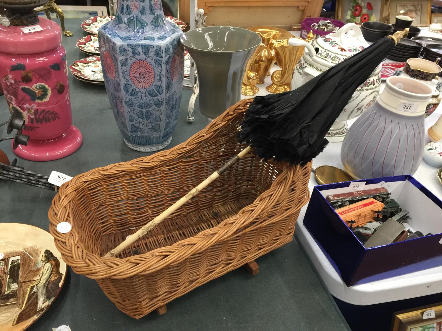 A CHILD'S/DOLL'S CARVED BONE HANDLED PARASOL AND A DOLL'S WICKER ROCKING CRADLE