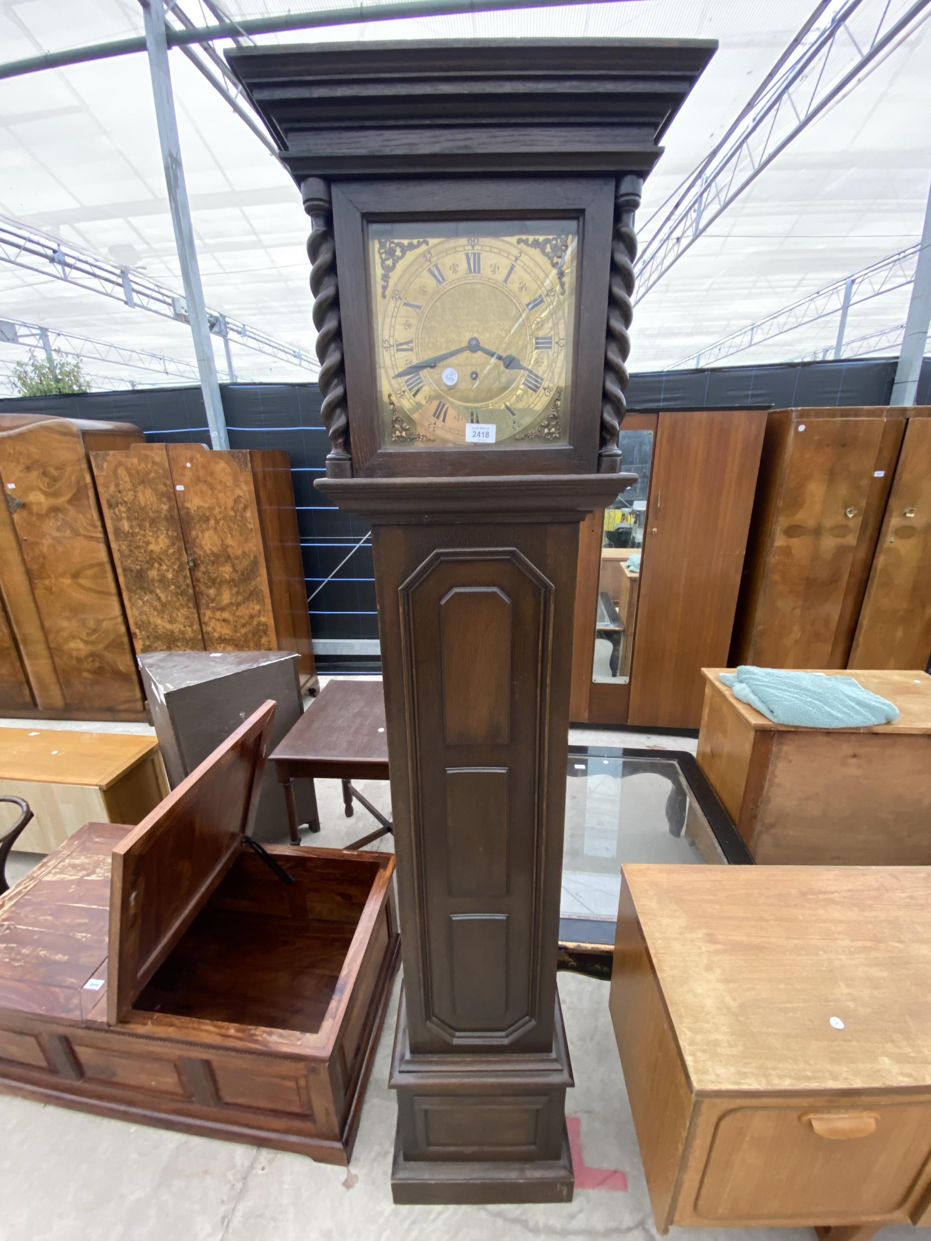 A OAK JACOBEAN STYLE BRASS FACED LONGCASE CLOCK WITH BARLEYTWIST UPRIGHTS