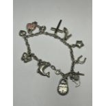 A SILVER CHARM BRACELET WITH ELEVEN CHARMS TO INCLUDE KEYS, HEARTS, DOLPHIN, CROSS, HANDBAG ETC