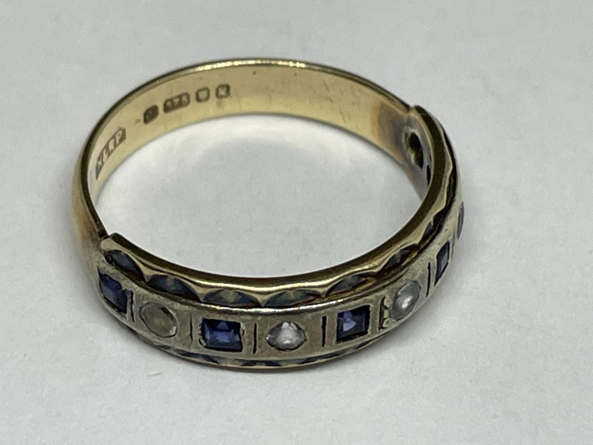 A 9 CARAT GOLD RING WITH FIVE SQUARE SAPPHIRES AND FIVE CLEAR STONES IN A BAND SIZE K - Image 4 of 4