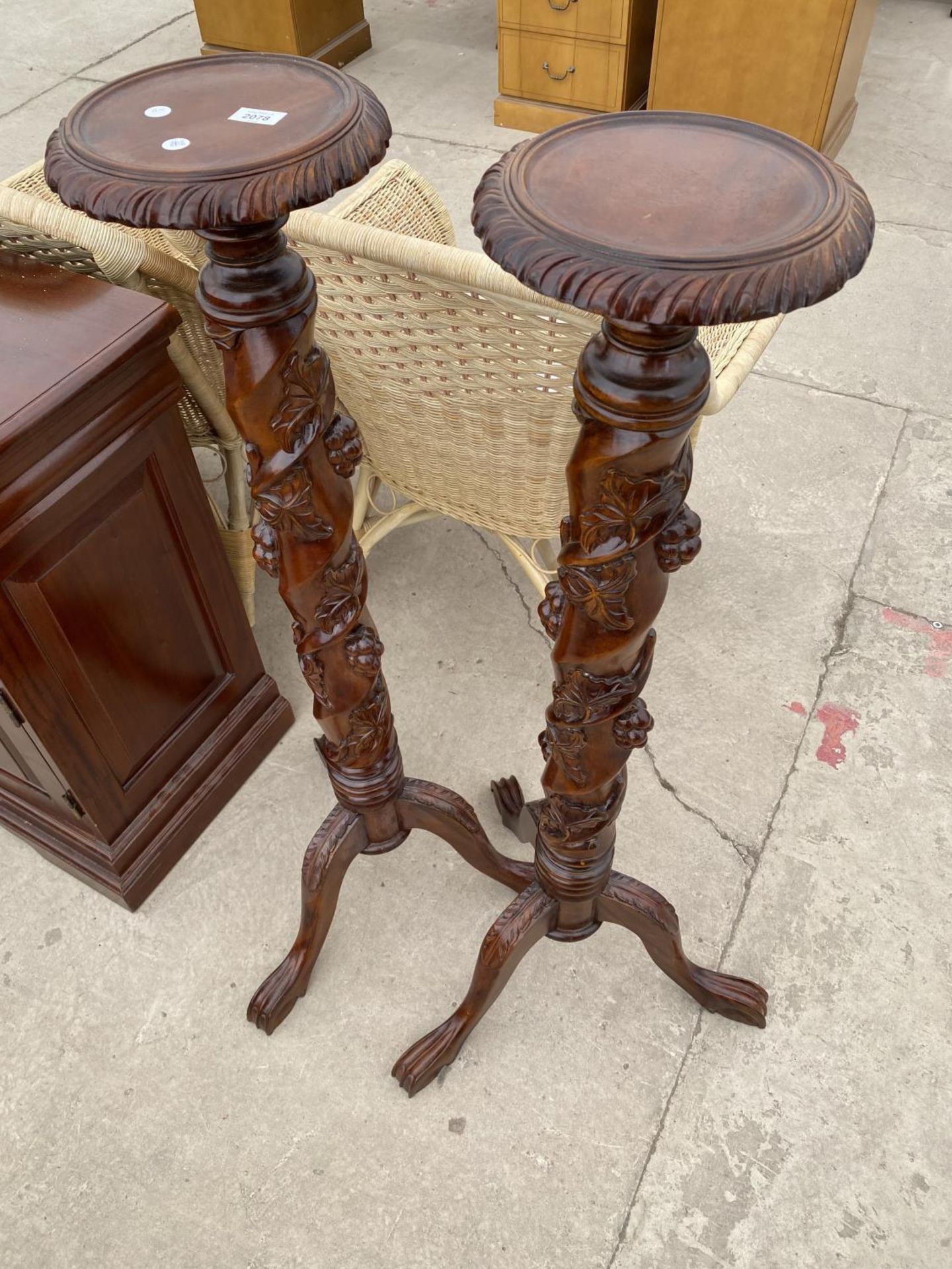 A PAIR OF VICTORIAN STYLE MAHOGANY TORCHERES ON TRIPOD BASES WITH FRUIT AND LEAF COLUMN DECORATION