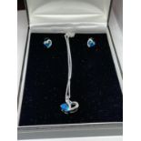 A SILVER NECKLACE WITH A BLUE AND CLEARSTONE HEART SHAPED PENDANT AND MATCHING EARRINGS IN A