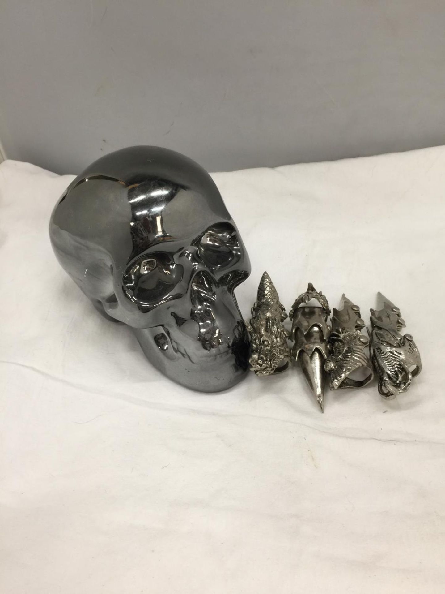 A CERAMIC SILVER COLOURED SKULL MONEY BOX AND FOUR JOINTED TALLON RINGS